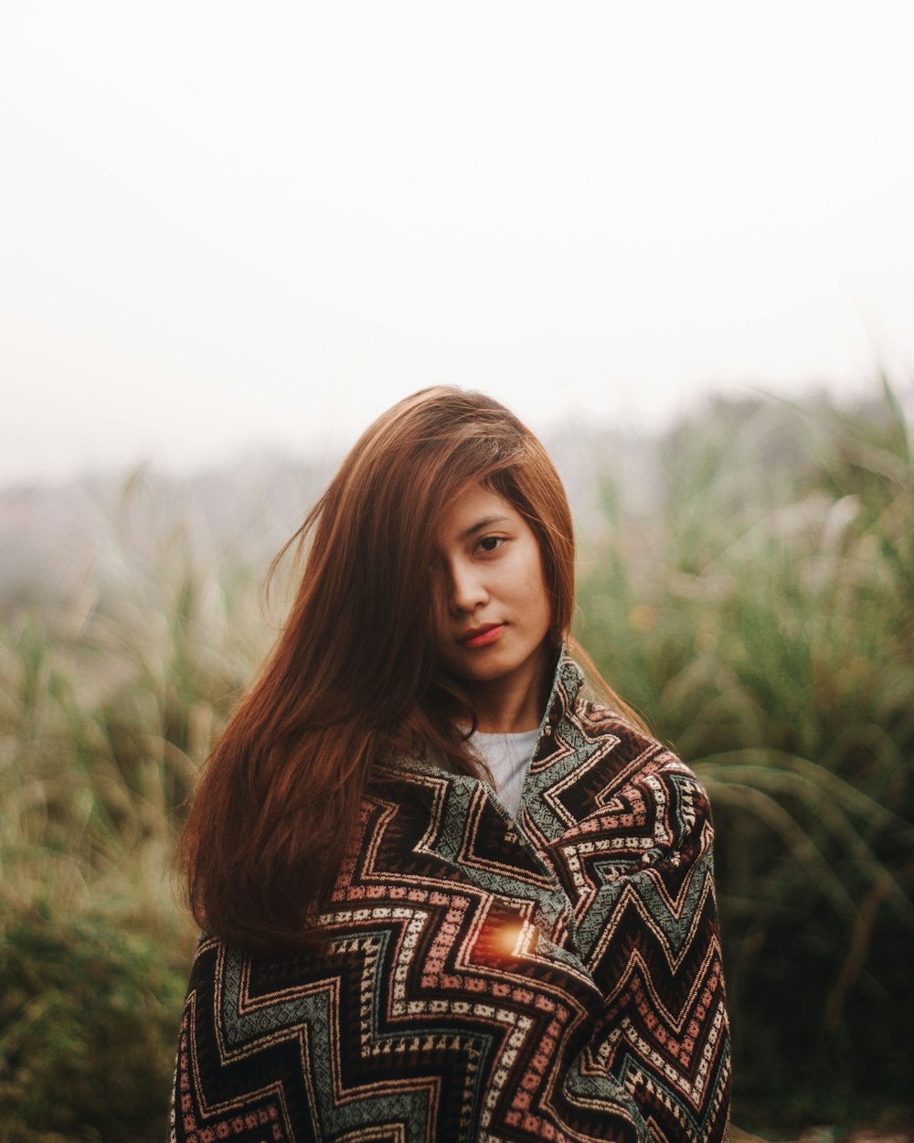 a woman with long hair standing in a field