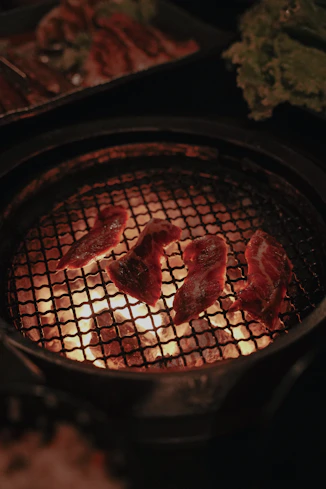 some meat is cooking on a grill in the dark