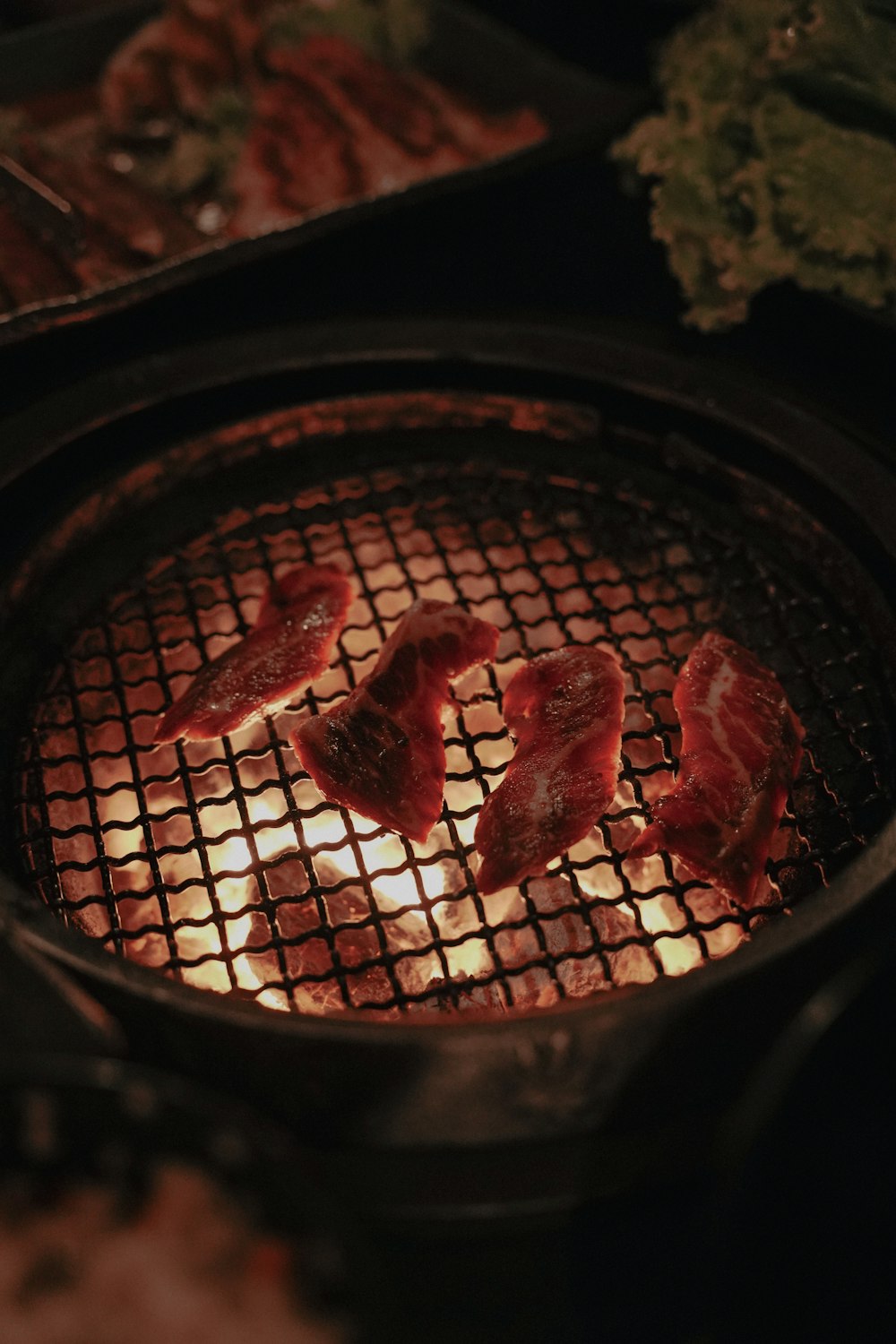 some meat is cooking on a grill in the dark