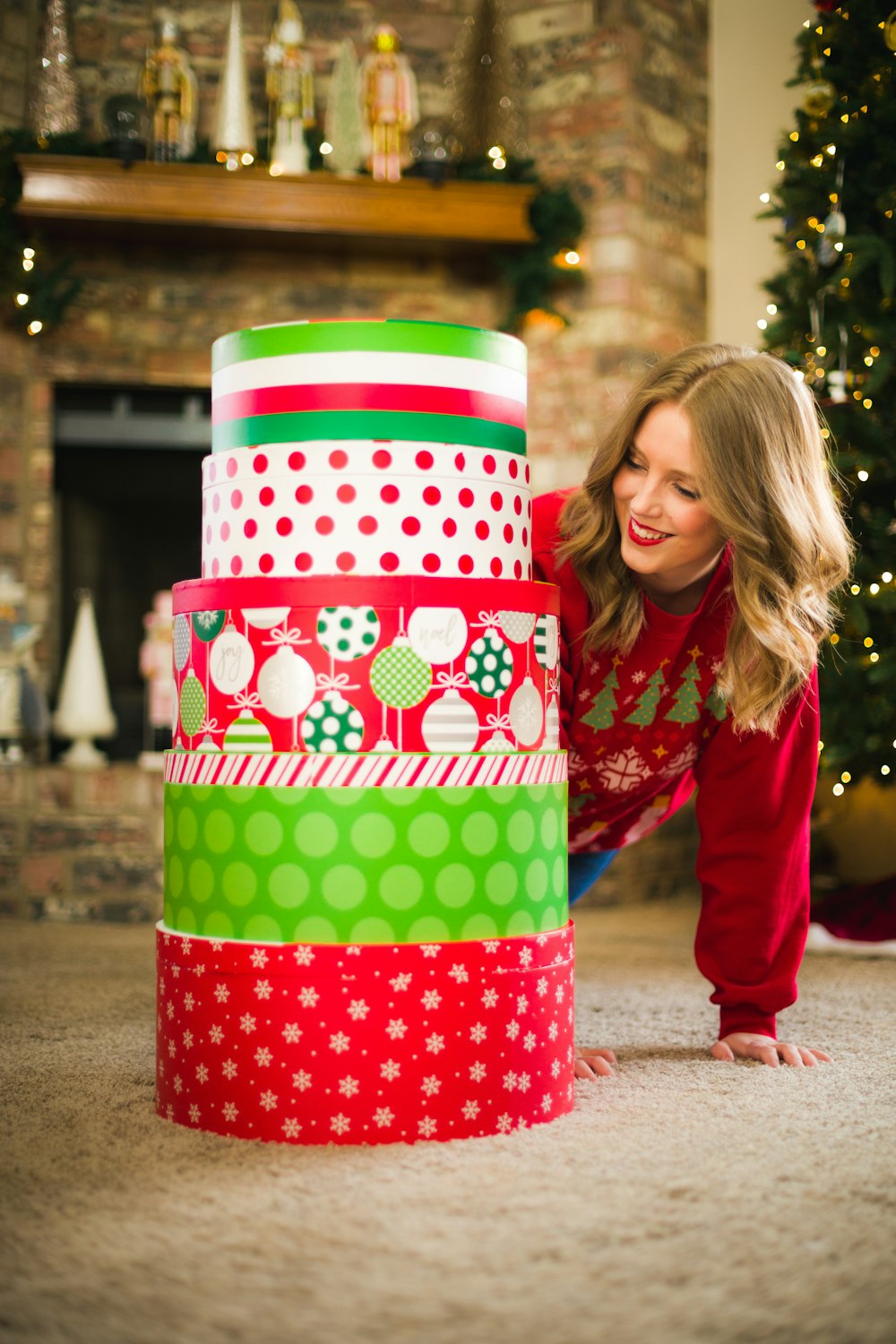 a woman leaning over a stack of christmas presents