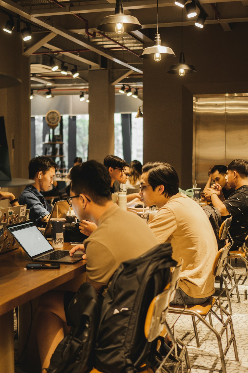 a group of people sitting at a table with laptops