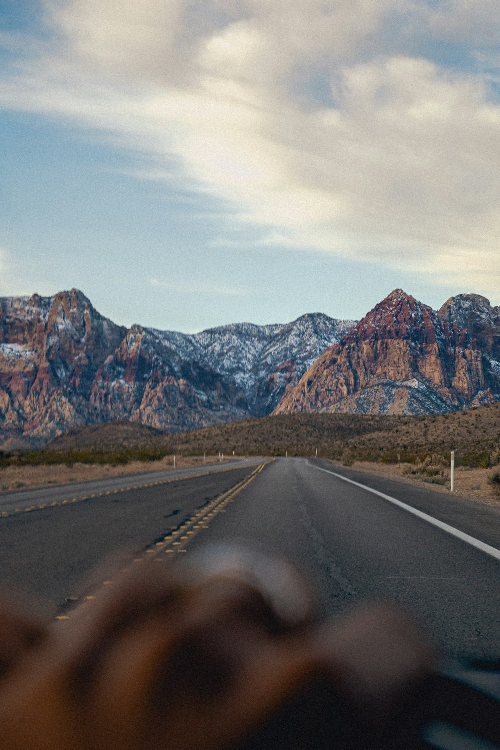 a person driving a car on a road with mountains in the background