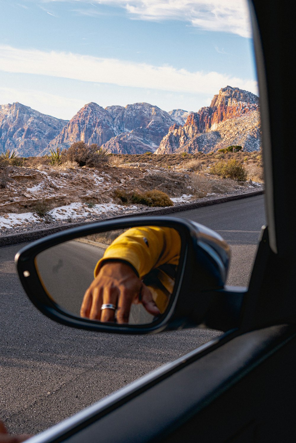 Una persona tomando una foto de montañas en un espejo retrovisor