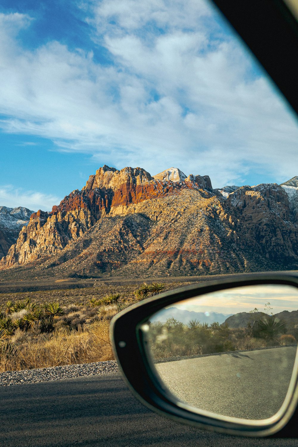 Una vista di una catena montuosa dallo specchietto retrovisore laterale di un'auto