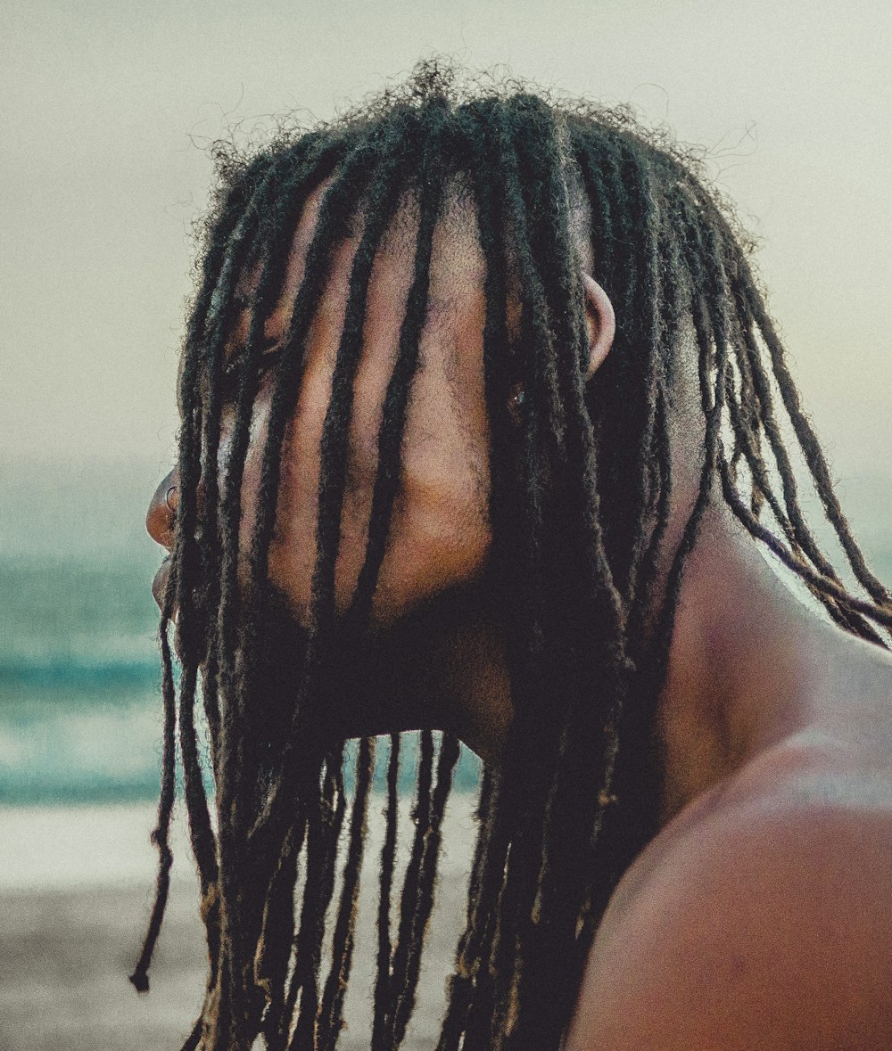 a man with dreadlocks standing on the beach