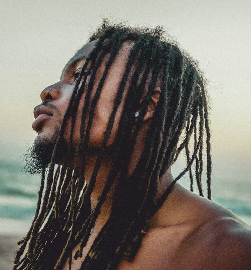 a man with dreadlocks standing on the beach