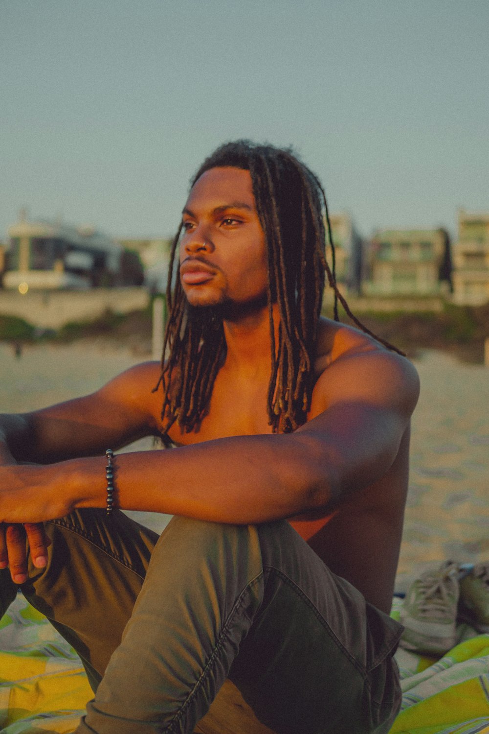 a man with dreadlocks sitting on a blanket on the beach