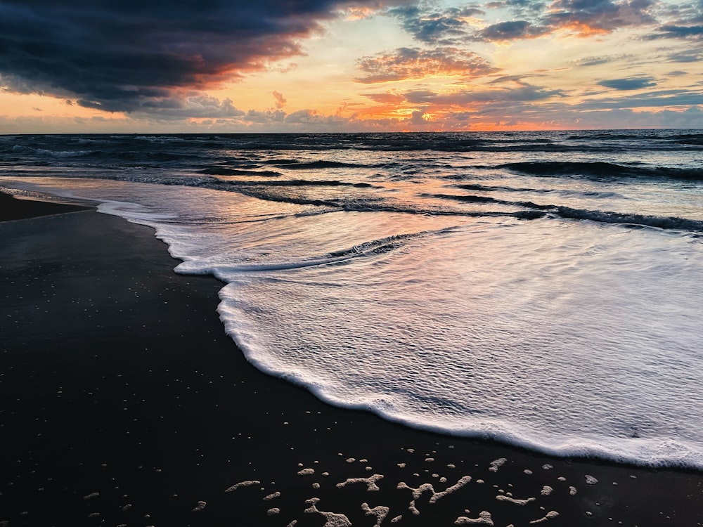 the sun is setting over the ocean with the word love written in the sand