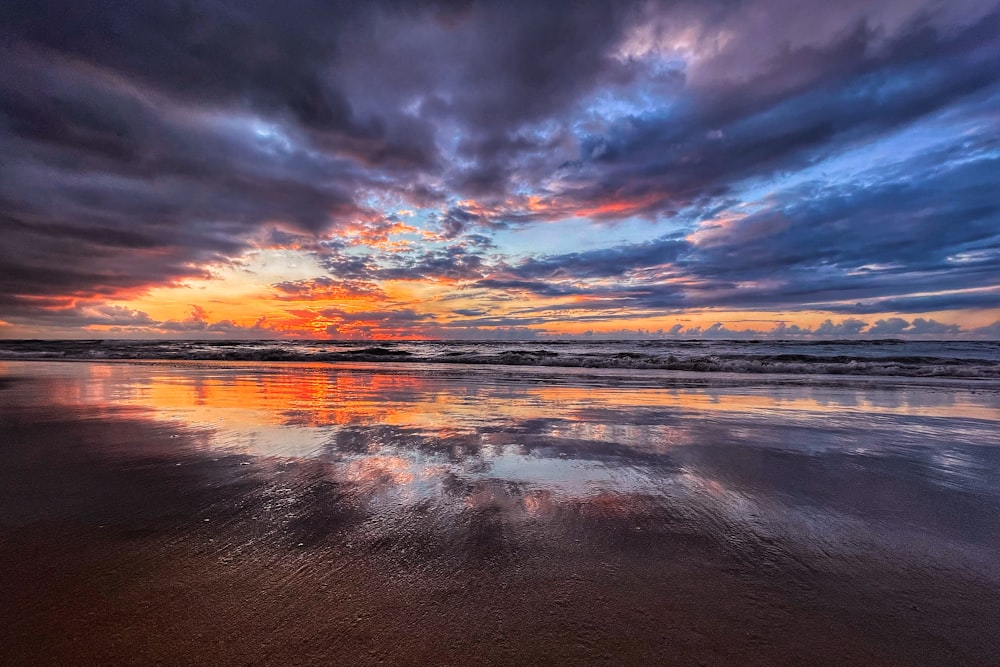 the sun is setting over the ocean on the beach