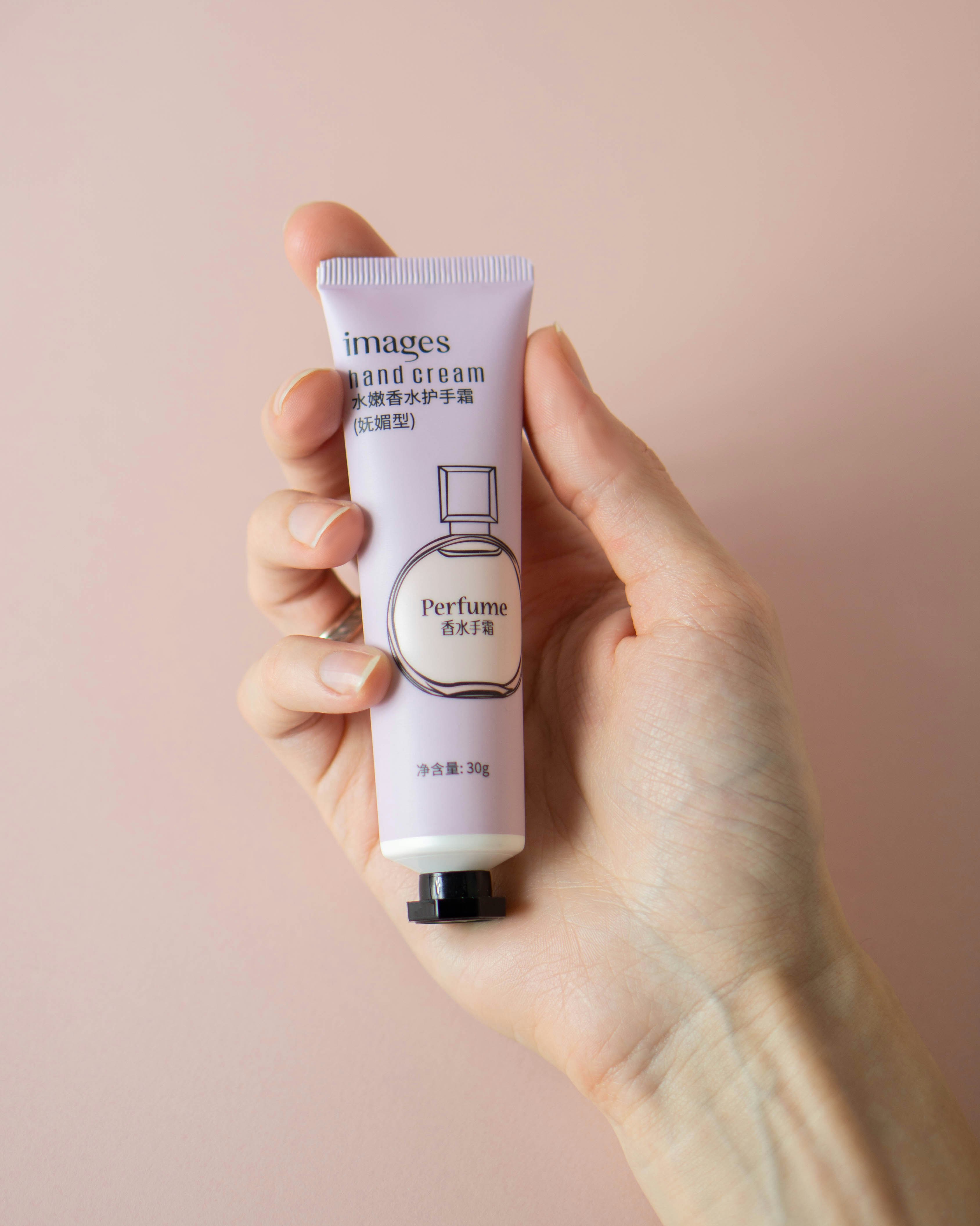 a hand holding a tube of hand cream