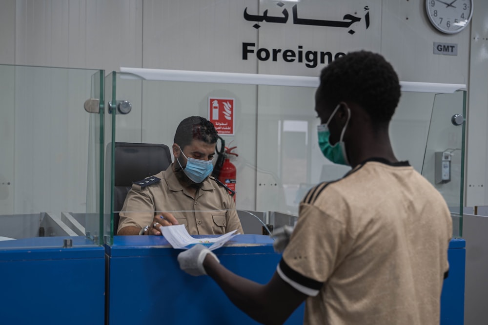 a man wearing a face mask and gloves standing in front of a counter