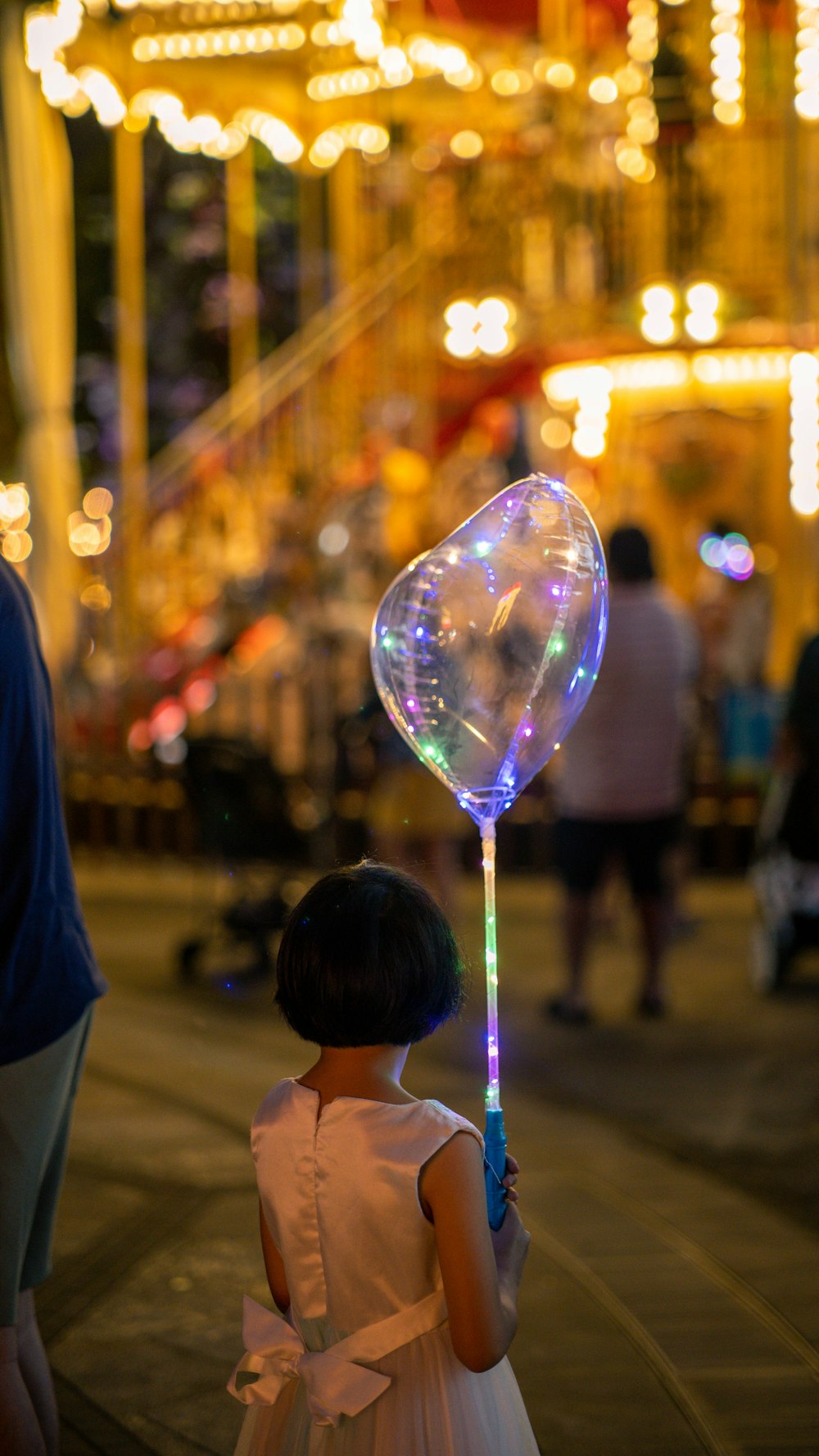 a little girl in a white dress holding a balloon