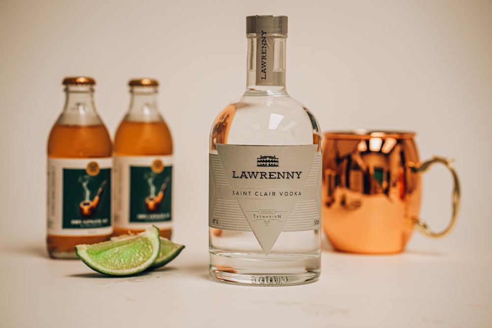 a bottle of lawenny gin next to two copper mugs
