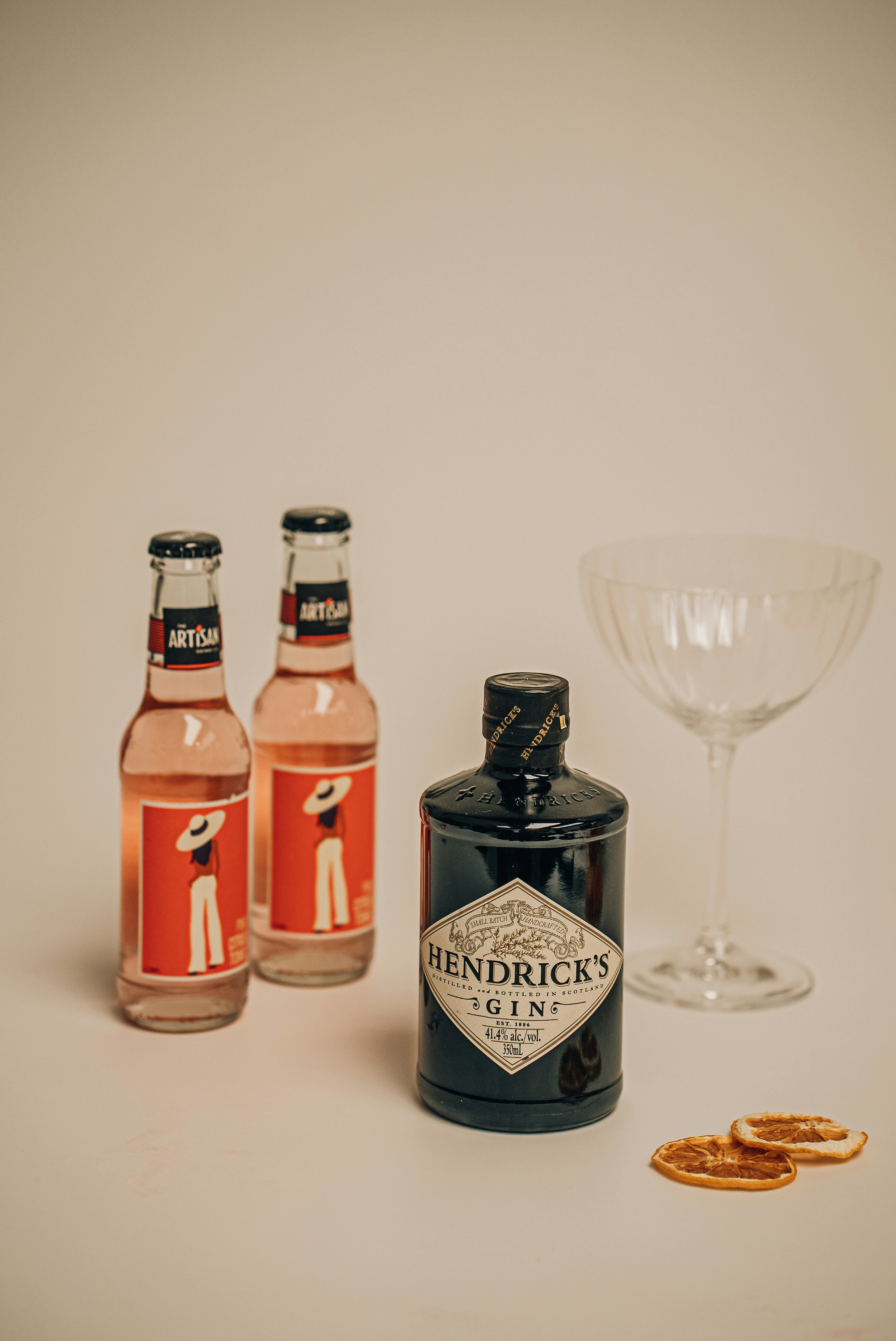 three bottles of gin next to a glass