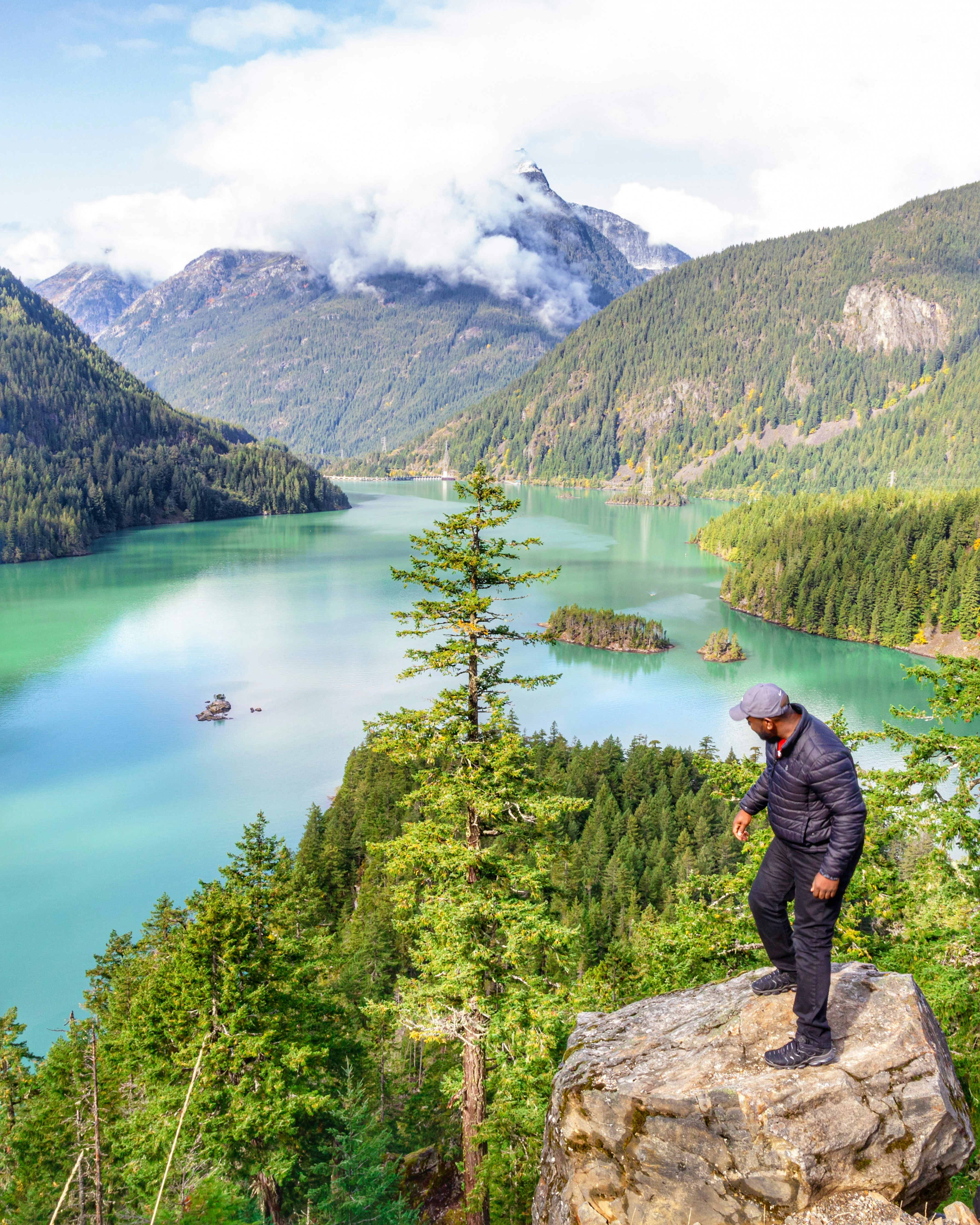 a man standing on top of a rock next to a lake
