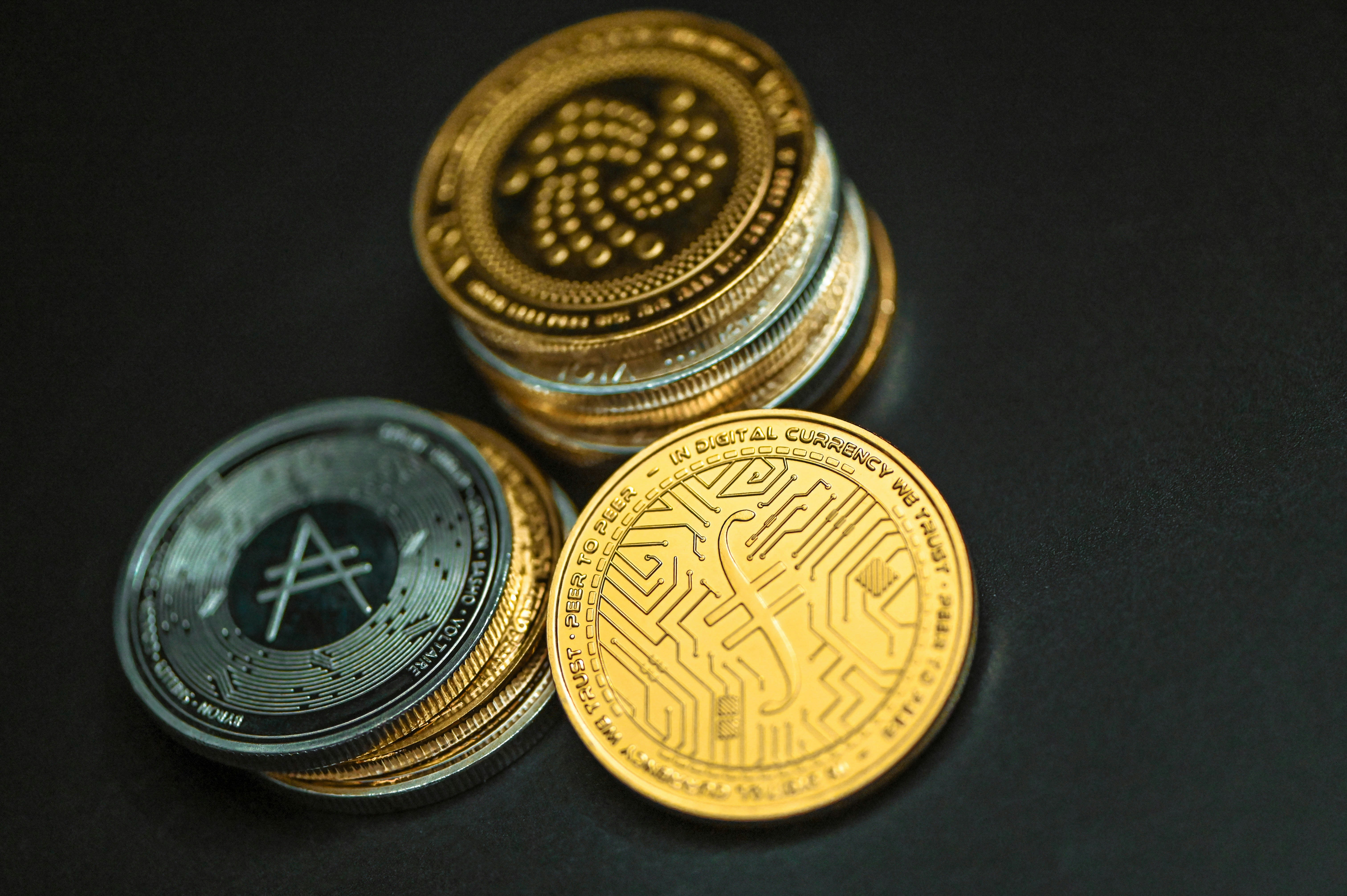 A pile of cryptocurrency coins placed on a black background