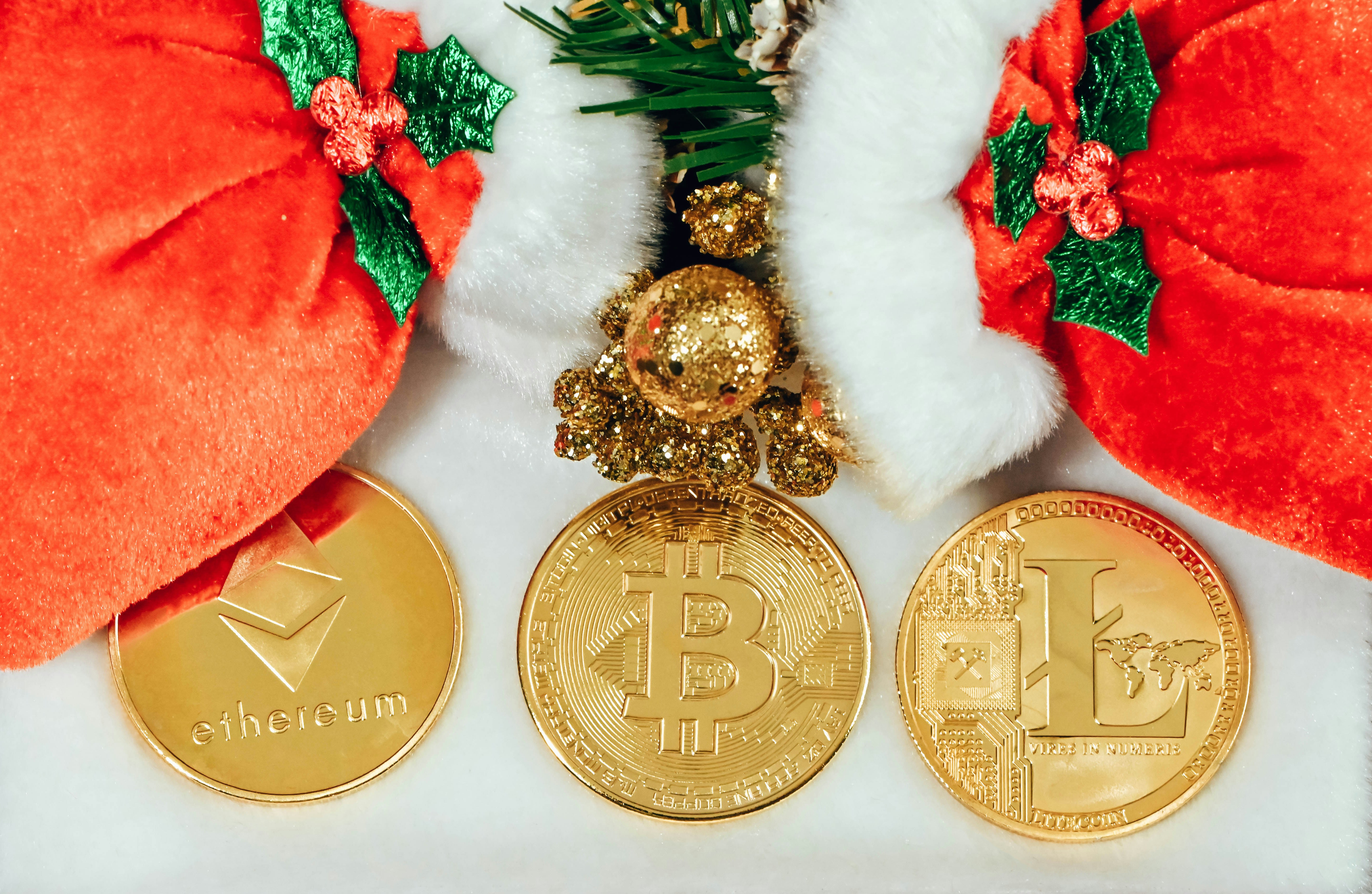 Ethereum coin, Bitcoin, and Litecoin under two Santa Claus hats