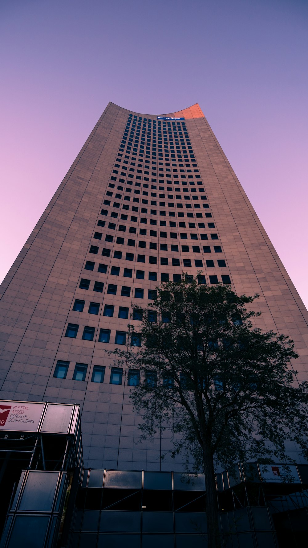 Un edificio alto con un árbol frente a él