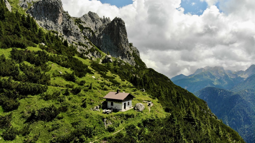 a house on the side of a mountain with mountains in the background