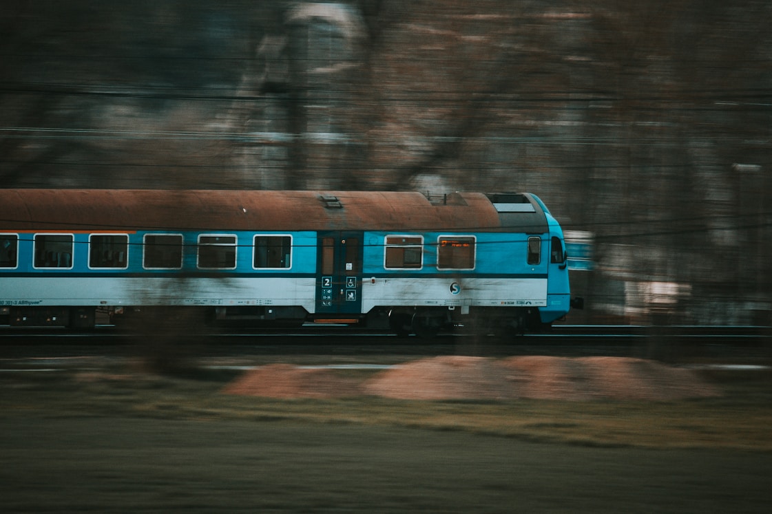 a blue and white train traveling down train tracks