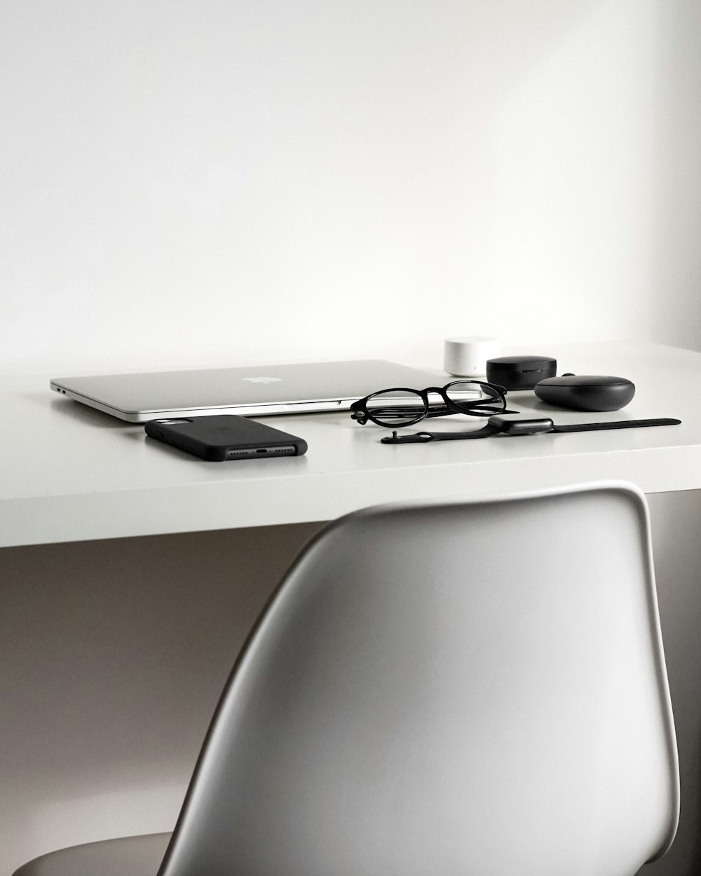 a white desk with a laptop and a pair of glasses