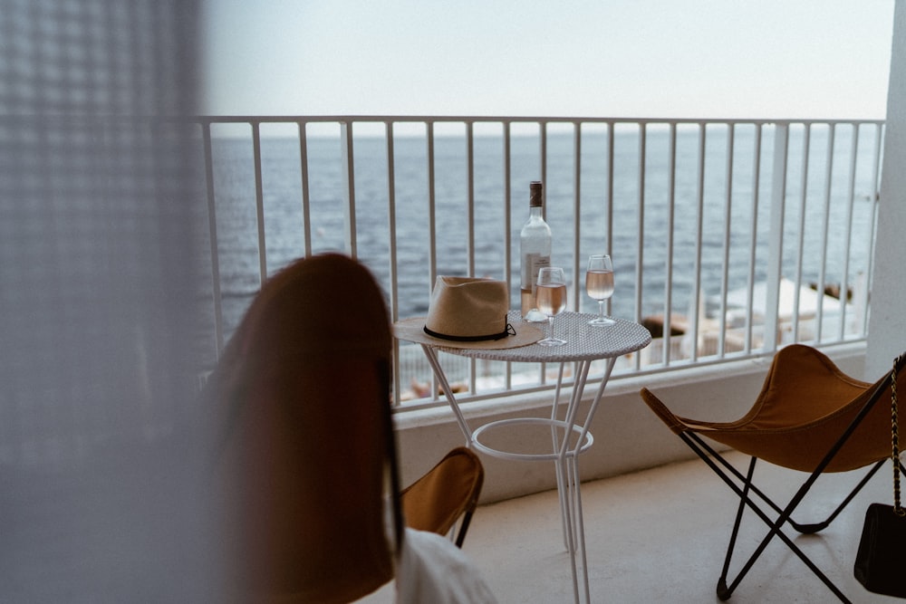 un balcon avec deux chaises et une table avec un chapeau dessus