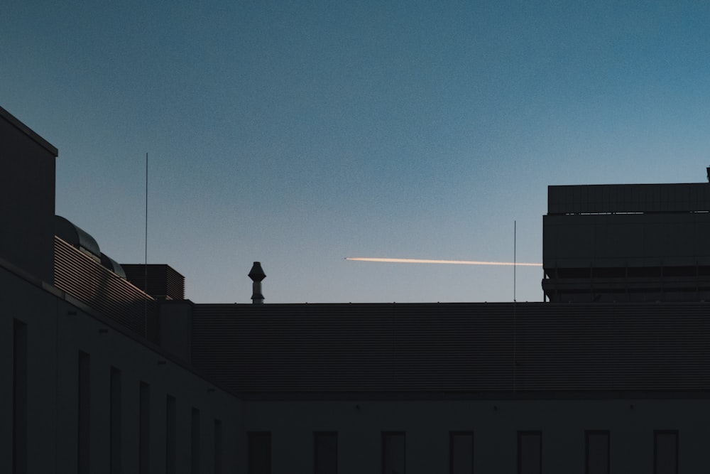 a person standing on top of a roof next to a tall building