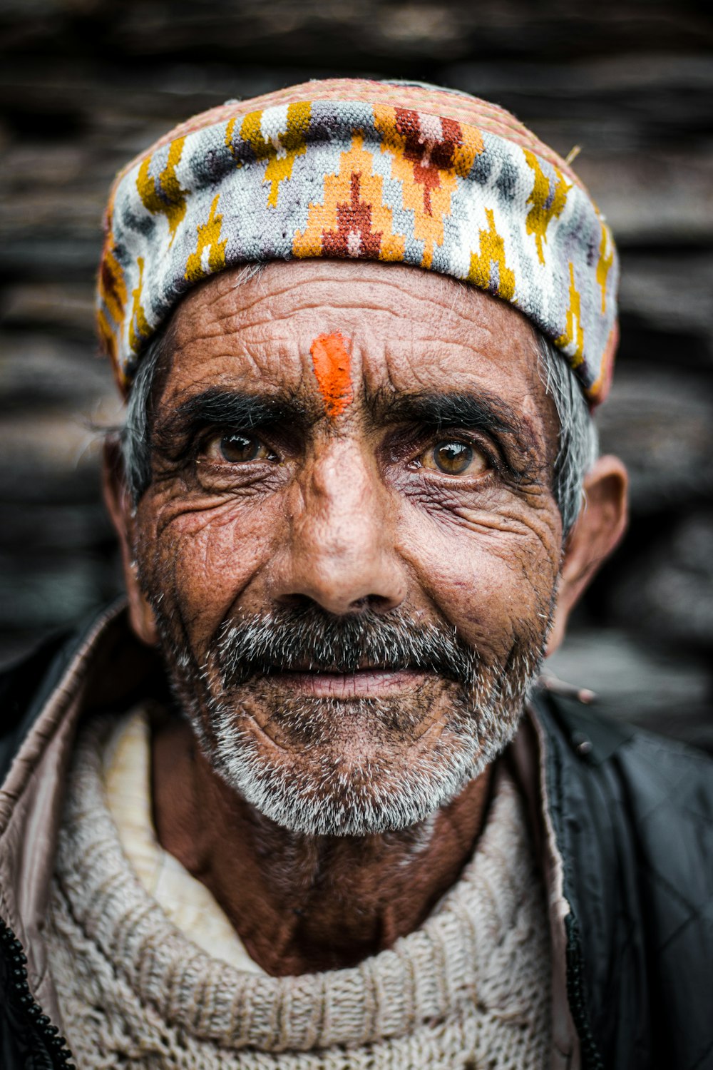 um homem velho com um turbante colorido na cabeça