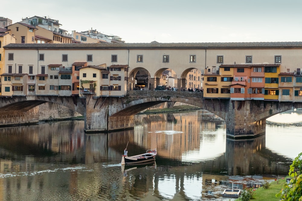 a small boat floating on top of a river under a bridge