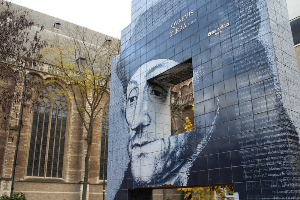 un grand bâtiment avec une peinture murale du visage d’un homme