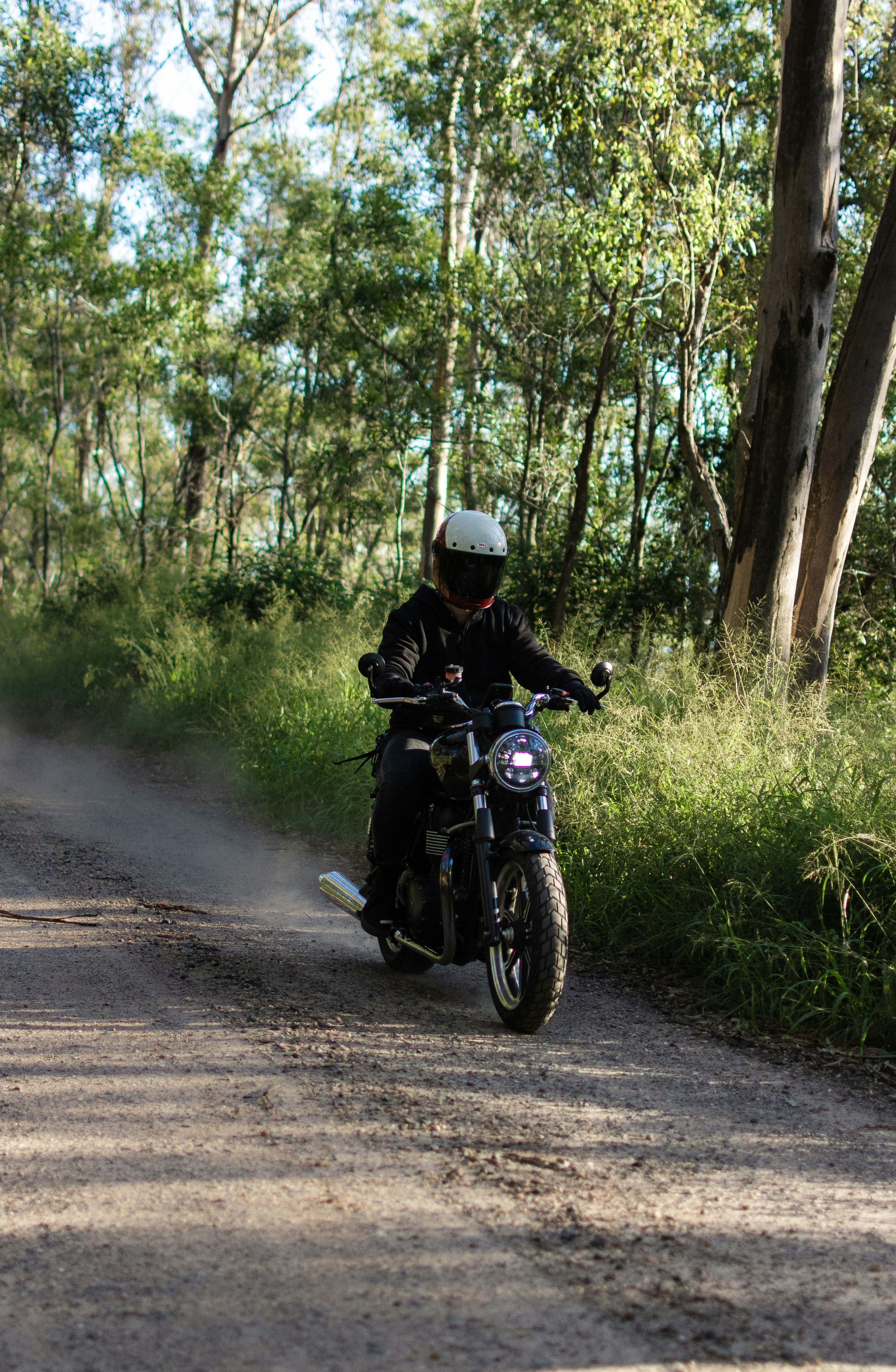 a man riding a motorcycle down a dirt road