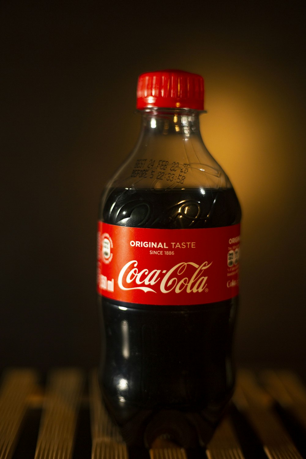 a bottle of coca cola sitting on top of a wooden table