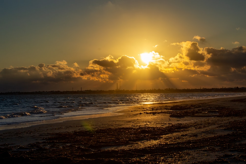 the sun is setting over the ocean on the beach