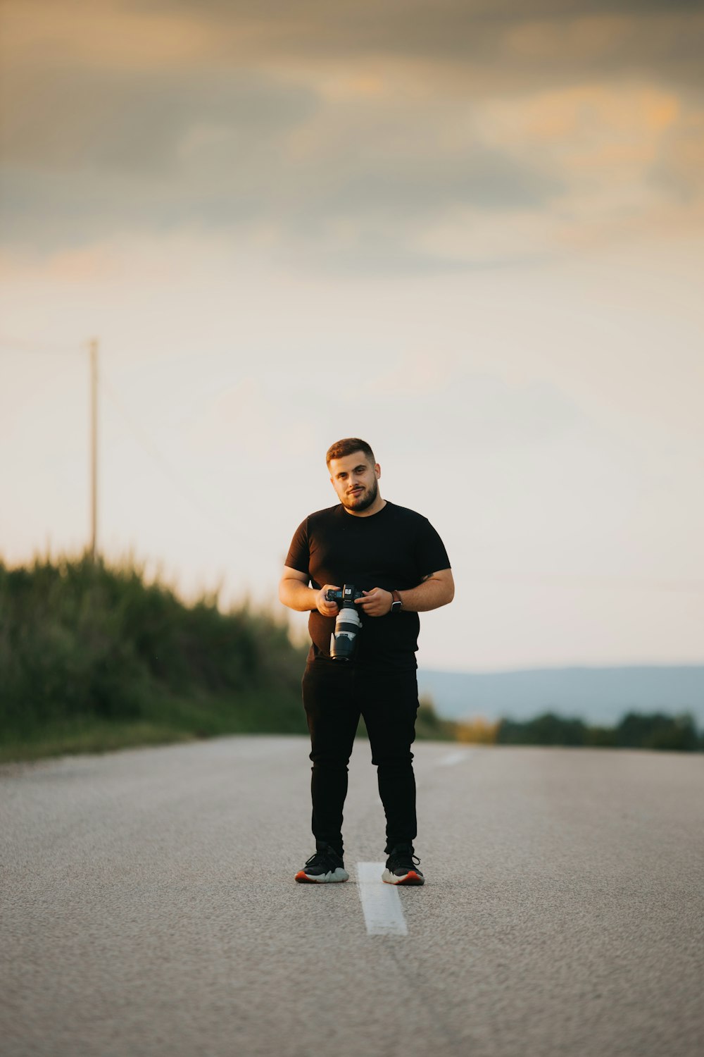 a man standing on the side of a road holding a camera