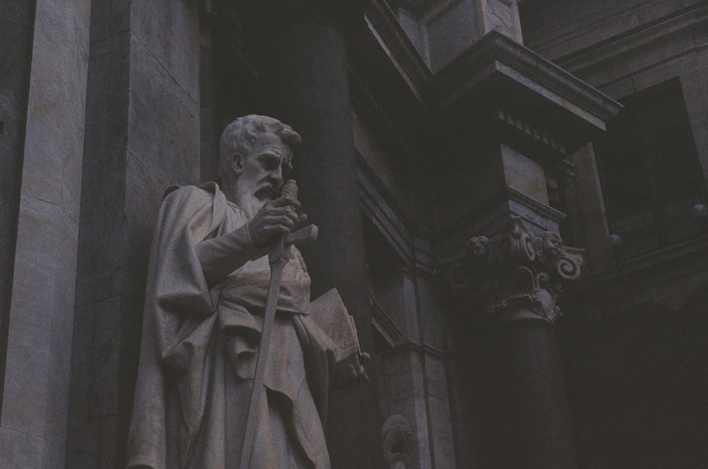 Una estatua de un hombre de pie junto a un edificio alto