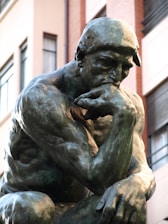 a bronze statue of a man with his hand on his face