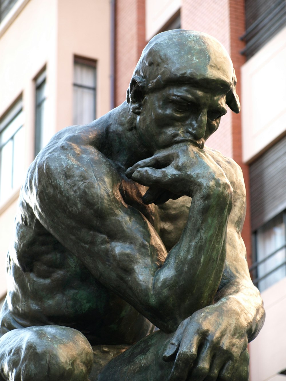 Una estatua de bronce de un hombre con la mano en la cara