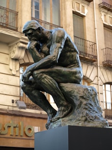 a statue of a man sitting in front of a building