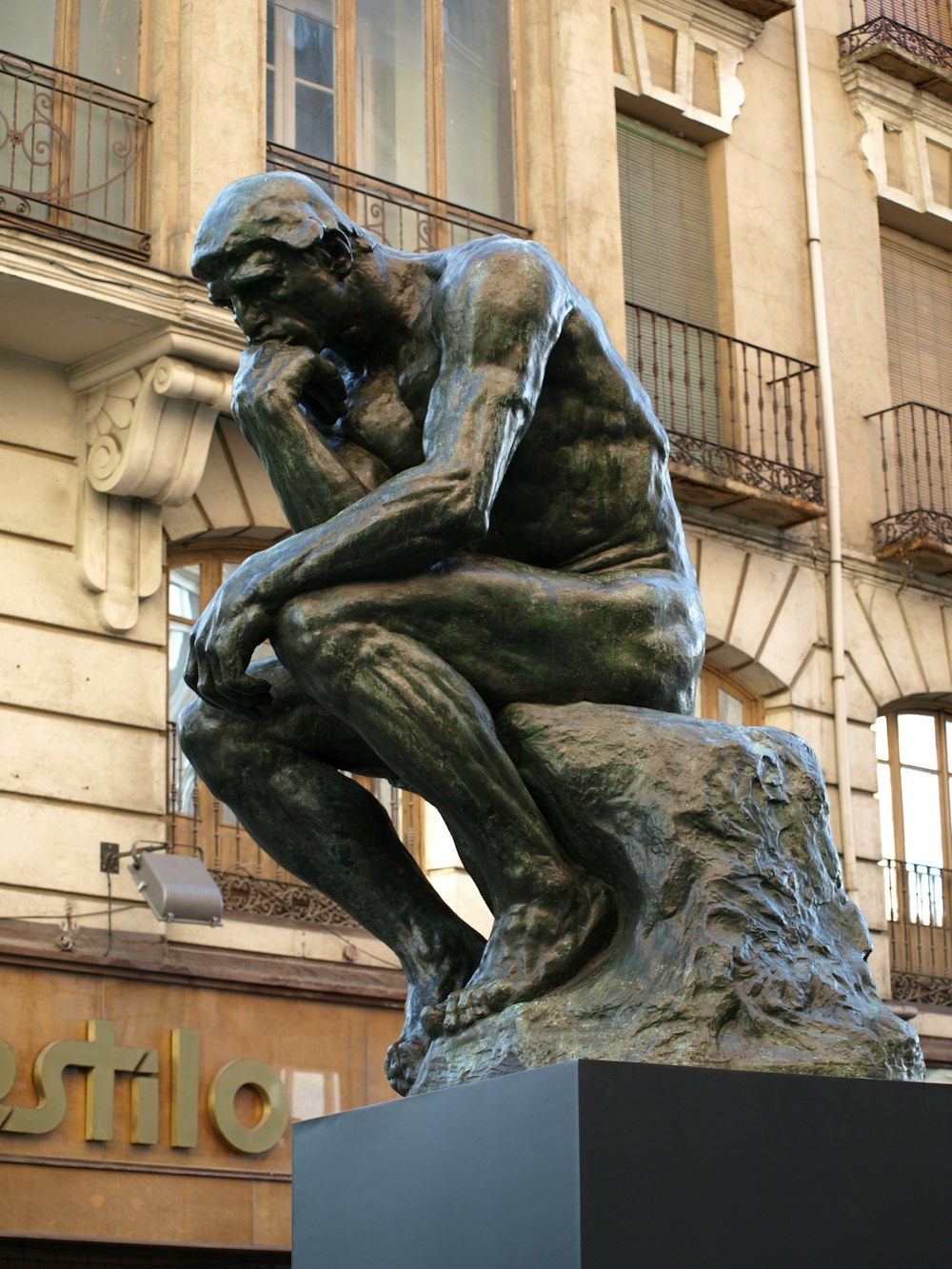une statue d’un homme assis devant un bâtiment