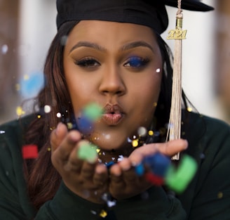 a woman in a graduation cap blowing bubbles