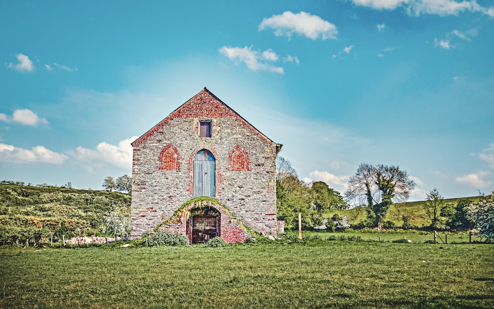 a brick building with a door in the middle of a field