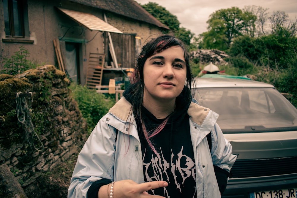 a woman standing in front of a parked car