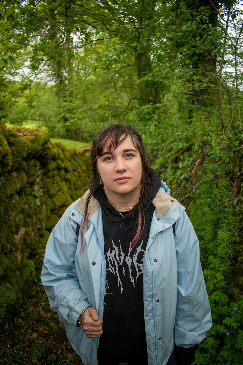 a woman in a blue jacket standing in a forest