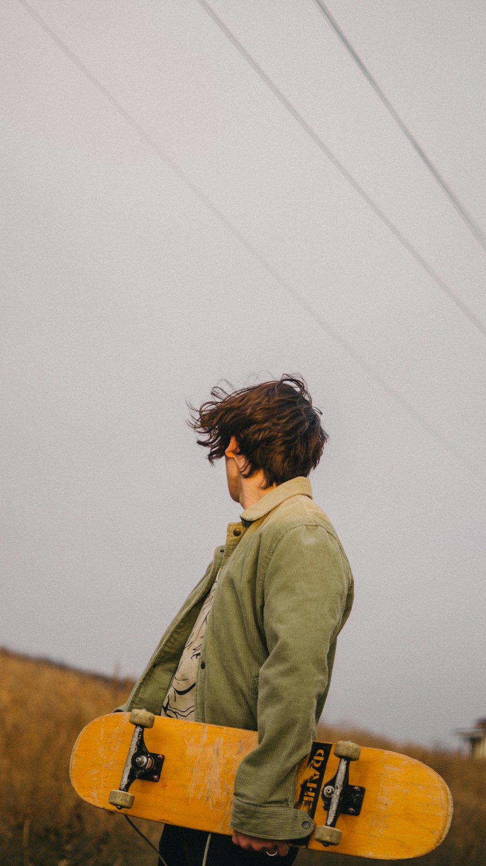 a man holding a yellow skateboard on top of a field