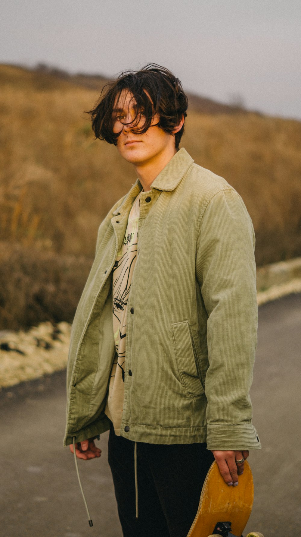 a man holding a skateboard on the side of a road