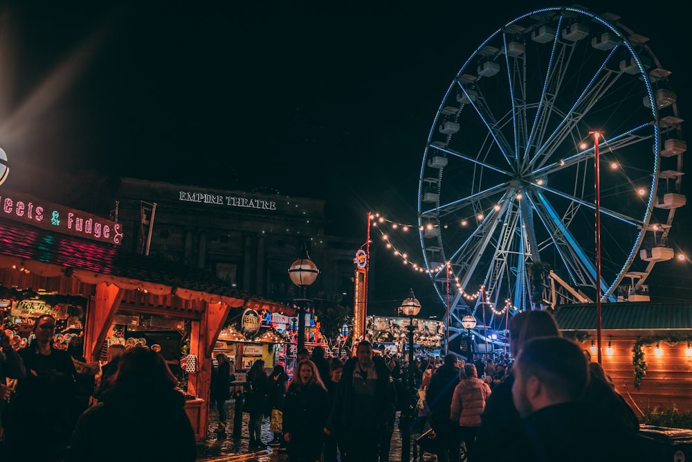 a crowd of people standing around a carnival at night