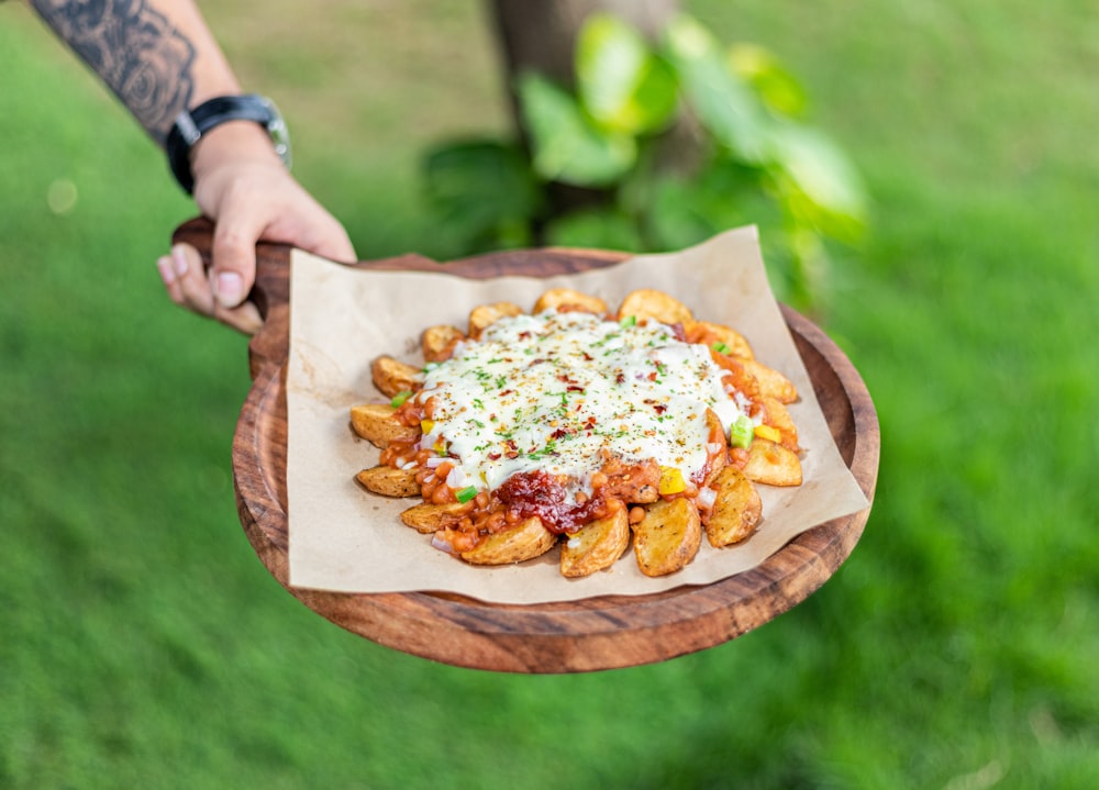 a person holding a plate of food on a table