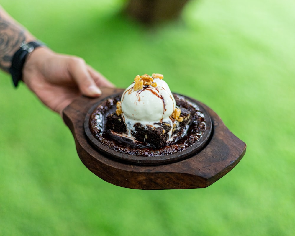 a person holding a chocolate dessert with ice cream on top