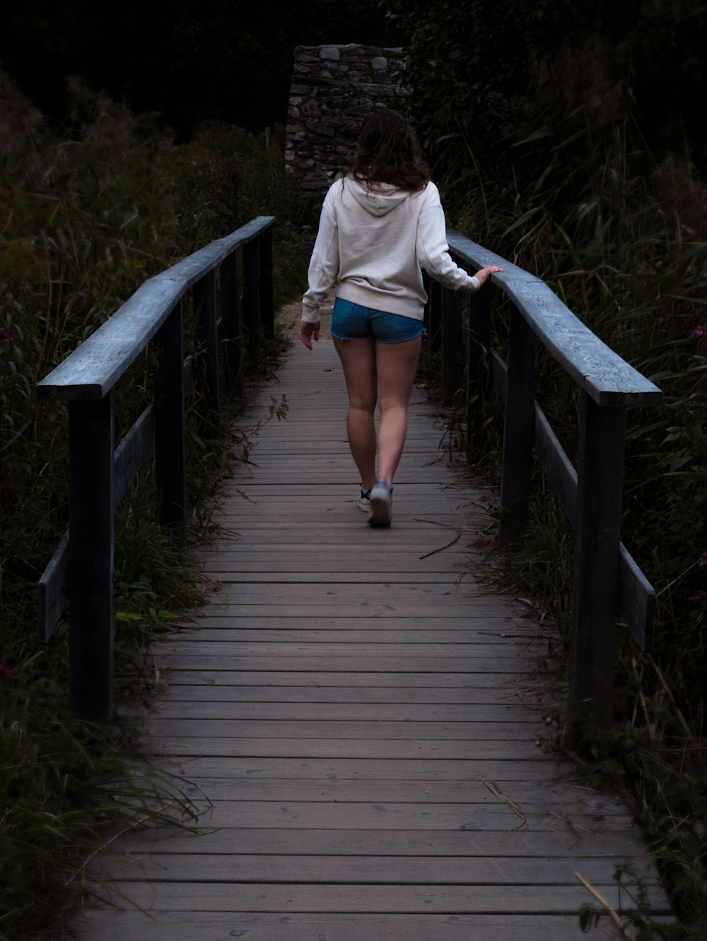 a woman walking across a wooden bridge at night