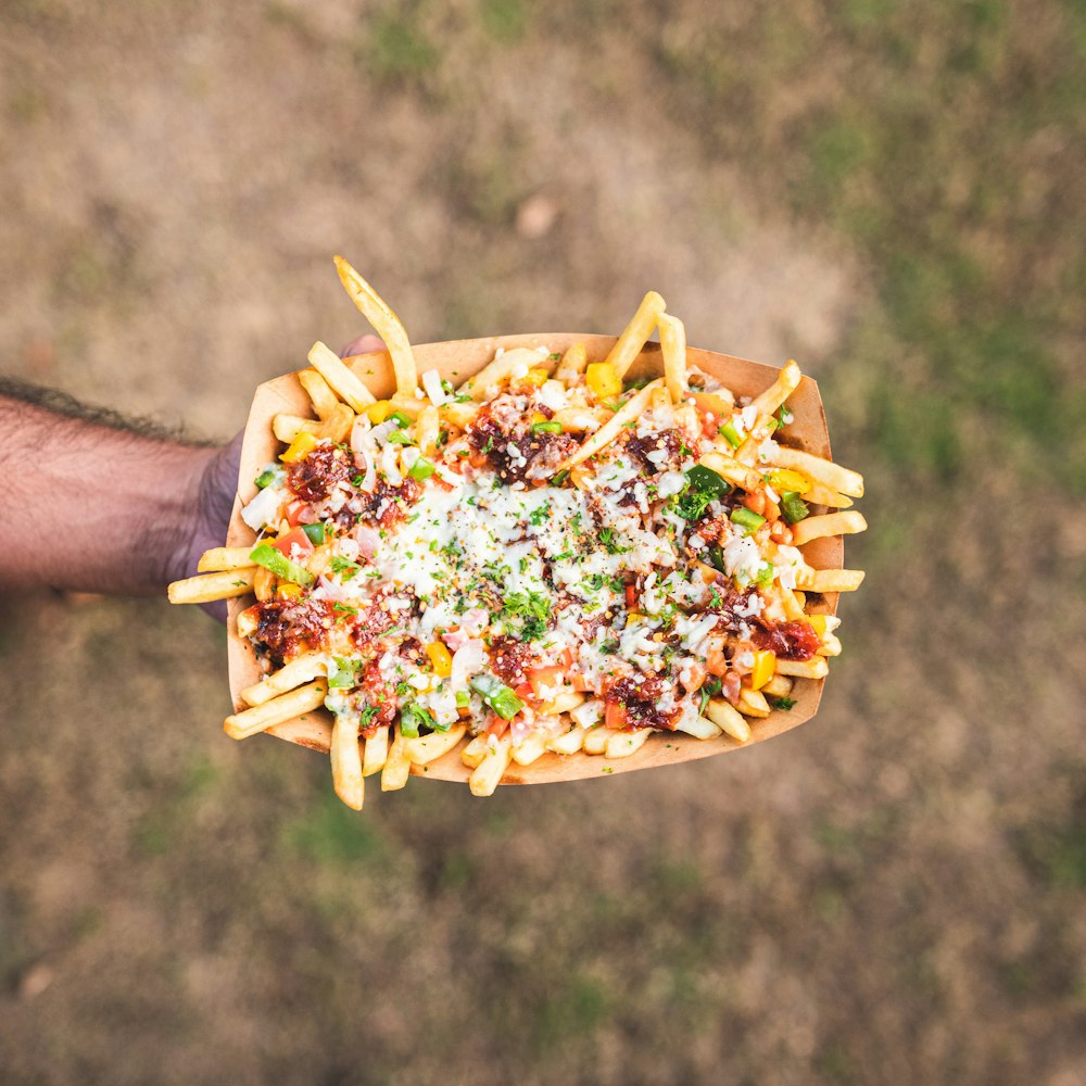 a person holding a tray of french fries